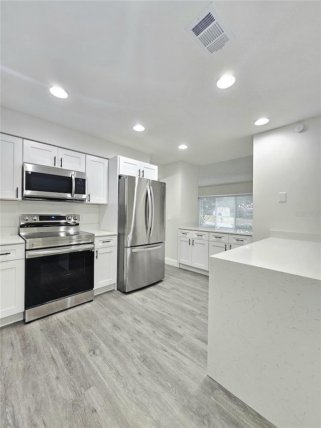 kitchen featuring appliances with stainless steel finishes, white cabinetry, and light wood-type flooring