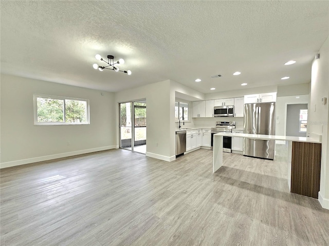 kitchen featuring stainless steel appliances, sink, white cabinetry, a textured ceiling, and a chandelier