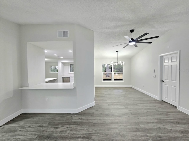 unfurnished living room with ceiling fan with notable chandelier, hardwood / wood-style flooring, a textured ceiling, and lofted ceiling