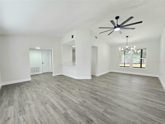 unfurnished living room featuring ceiling fan with notable chandelier, light wood-type flooring, vaulted ceiling, and a textured ceiling