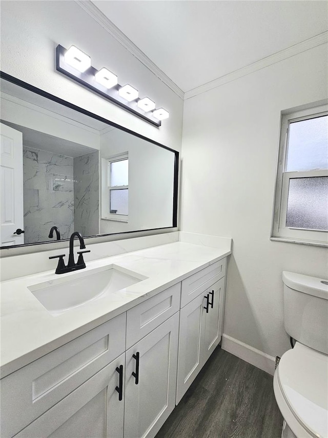 bathroom with toilet, wood-type flooring, tiled shower, crown molding, and vanity