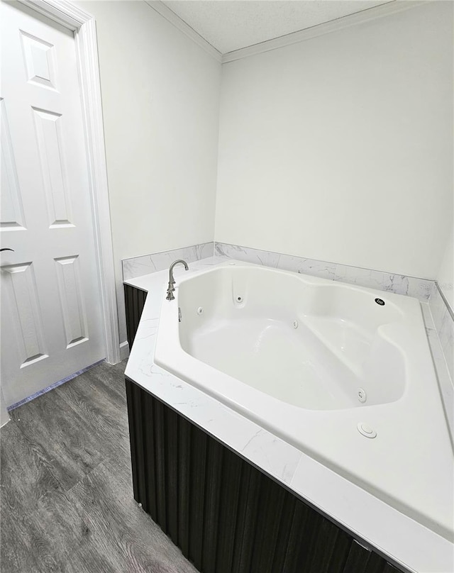 bathroom featuring a textured ceiling, a bathtub, hardwood / wood-style floors, and crown molding