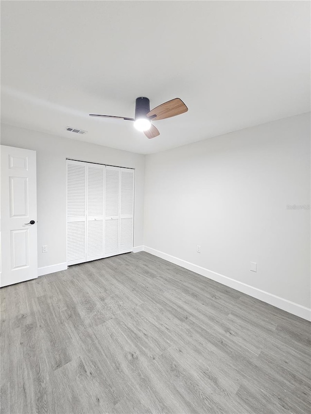 unfurnished bedroom featuring wood-type flooring, ceiling fan, and a closet