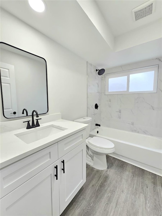 full bathroom with hardwood / wood-style flooring, toilet, vanity, and tiled shower / bath