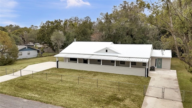 view of front of house featuring fence private yard, central AC, metal roof, and a front yard