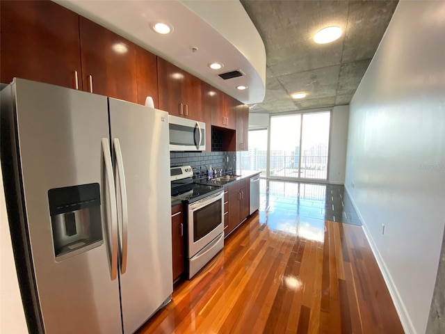 kitchen with hardwood / wood-style floors, decorative backsplash, sink, expansive windows, and stainless steel appliances