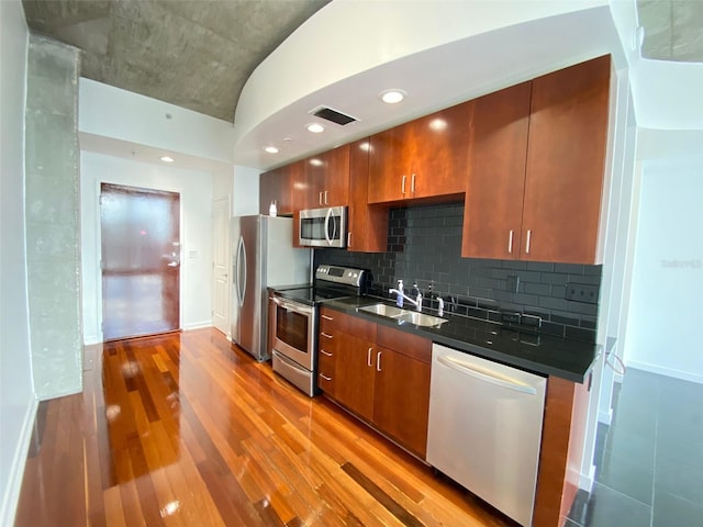 kitchen featuring tasteful backsplash, sink, stainless steel appliances, and light hardwood / wood-style flooring