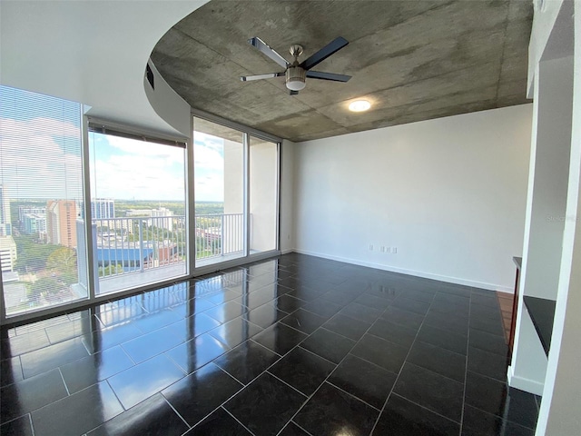 unfurnished room featuring ceiling fan and a wall of windows