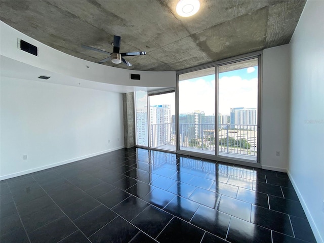 empty room featuring ceiling fan and a wall of windows