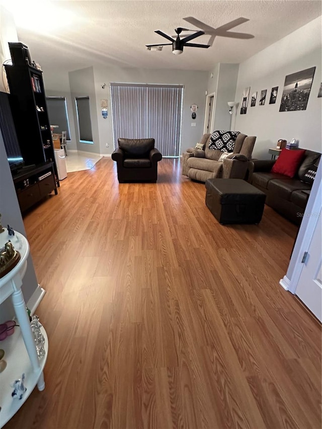 living room featuring a textured ceiling, ceiling fan, and wood-type flooring