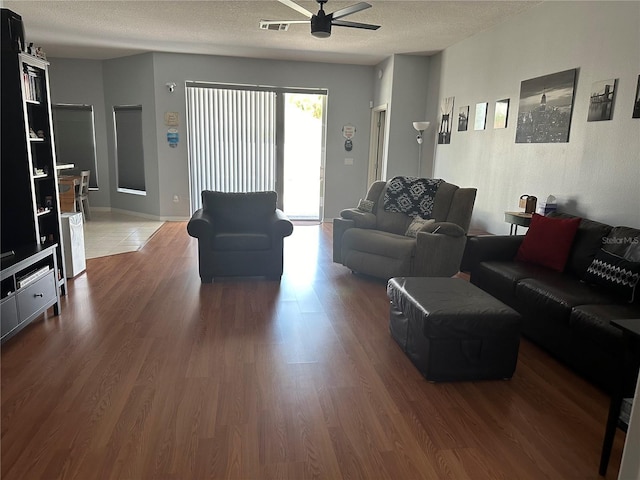 living room featuring ceiling fan, hardwood / wood-style floors, and a textured ceiling