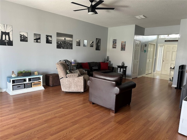 living room with hardwood / wood-style flooring, a textured ceiling, and ceiling fan