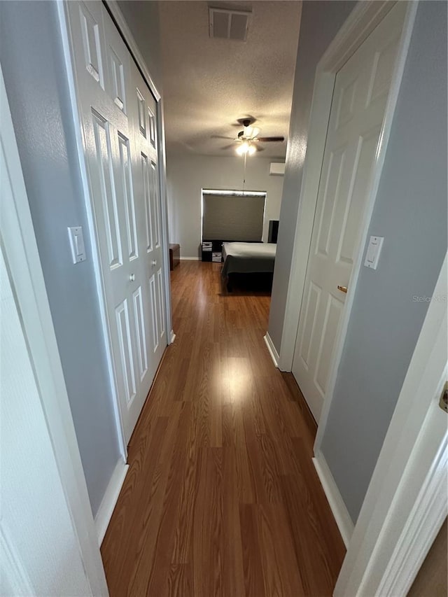 hallway with a textured ceiling and hardwood / wood-style floors