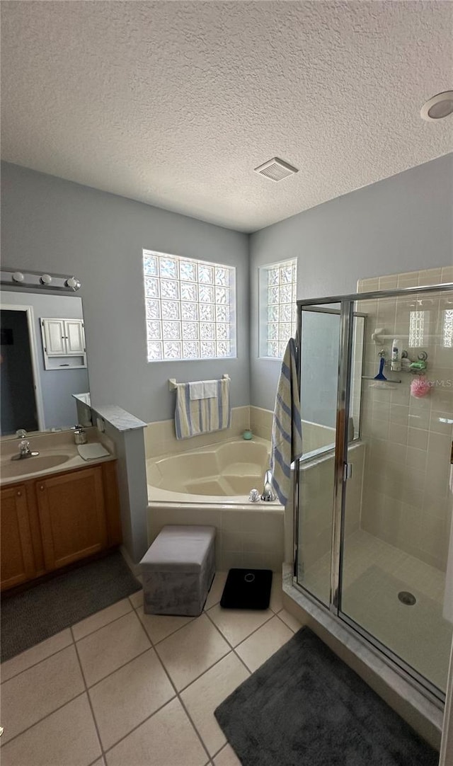 bathroom with a textured ceiling, tile patterned floors, independent shower and bath, and vanity