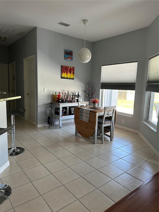 unfurnished dining area featuring bar area and light tile patterned floors