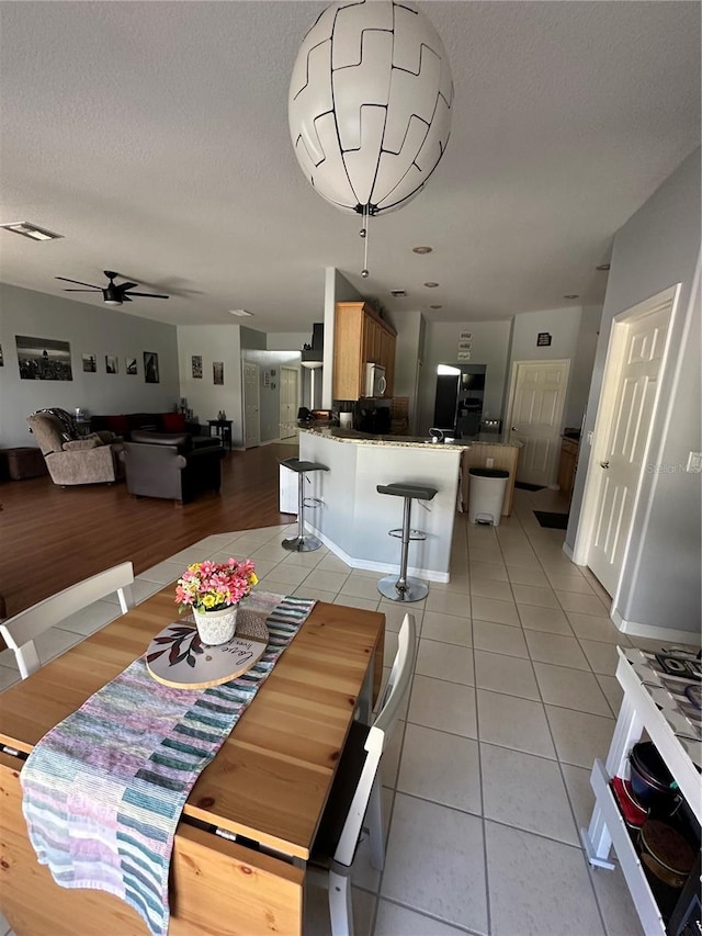 tiled dining space with ceiling fan and a textured ceiling