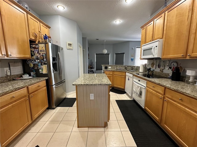 kitchen with white appliances, a center island, light tile patterned floors, and light stone counters