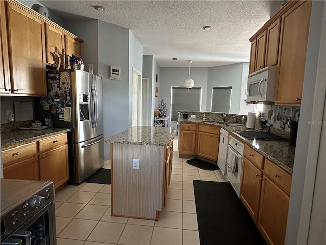 kitchen featuring a kitchen island, white appliances, dark stone countertops, and light tile patterned floors