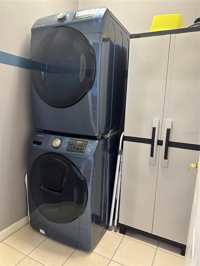 laundry room with light tile patterned floors and stacked washer / dryer