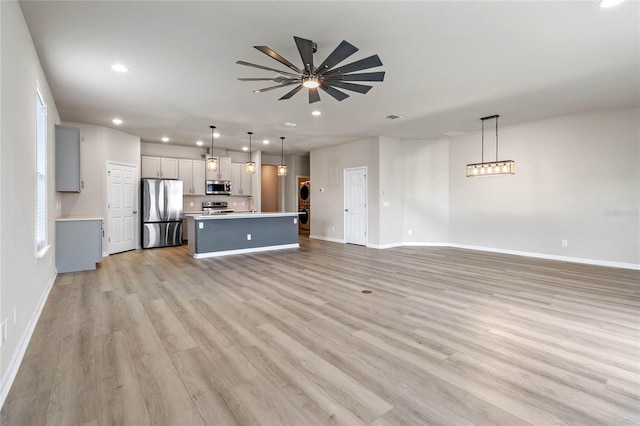 unfurnished living room featuring ceiling fan, light hardwood / wood-style flooring, and sink