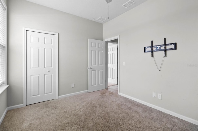 unfurnished bedroom featuring light colored carpet and a closet