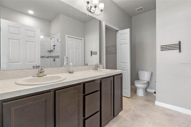 bathroom with tiled shower, tile patterned flooring, vanity, and toilet