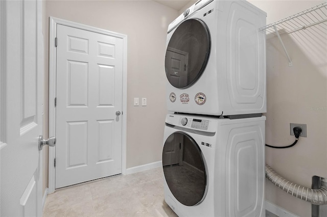 clothes washing area featuring stacked washer and clothes dryer and light tile patterned floors