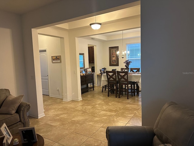 tiled living room with an inviting chandelier and a raised ceiling