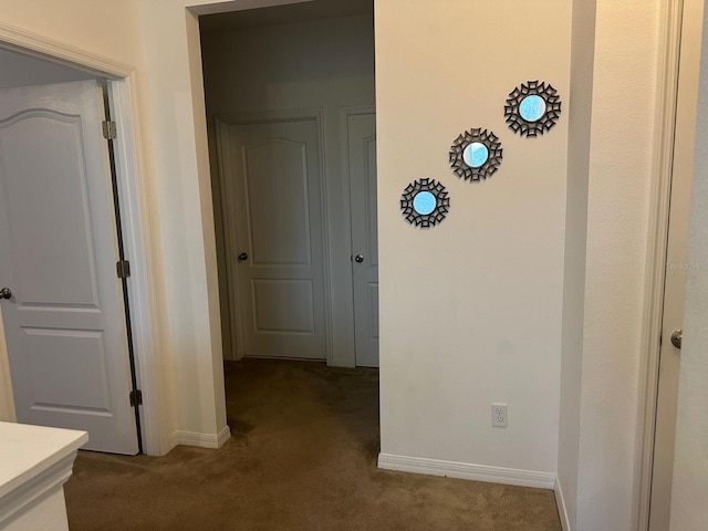 hall with dark colored carpet