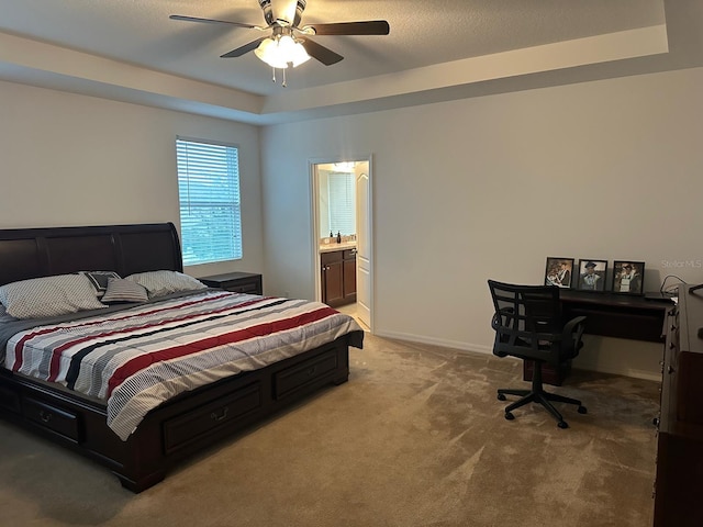 carpeted bedroom featuring ensuite bath, ceiling fan, and a raised ceiling