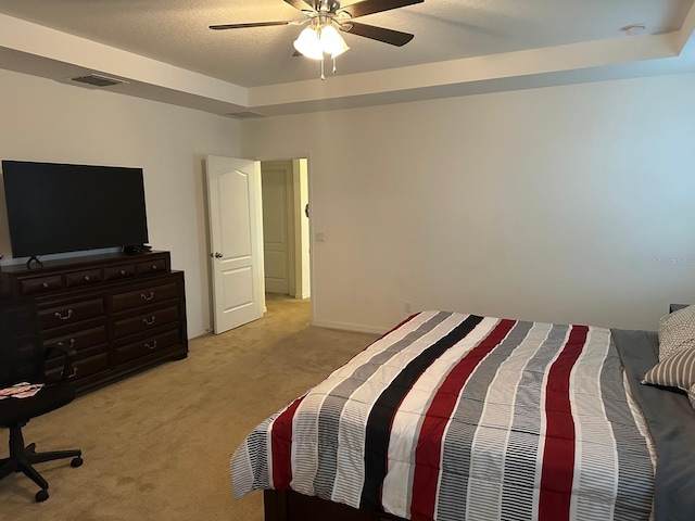 carpeted bedroom featuring a tray ceiling and ceiling fan