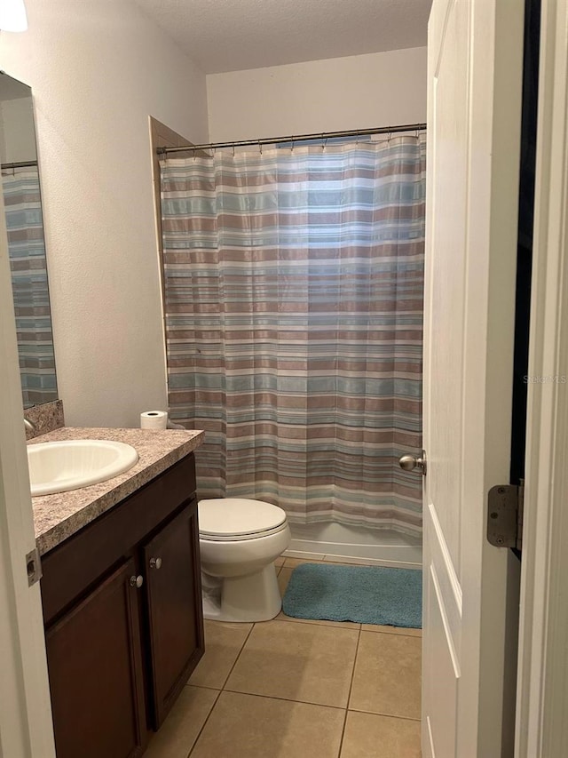 bathroom featuring vanity, toilet, tile patterned floors, and a textured ceiling