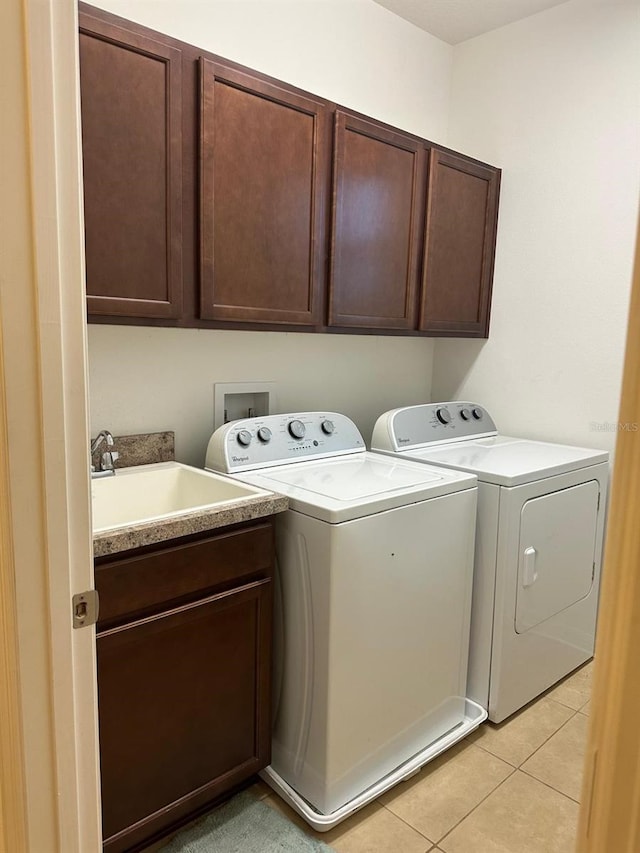 laundry area with sink, cabinets, separate washer and dryer, and light tile patterned flooring