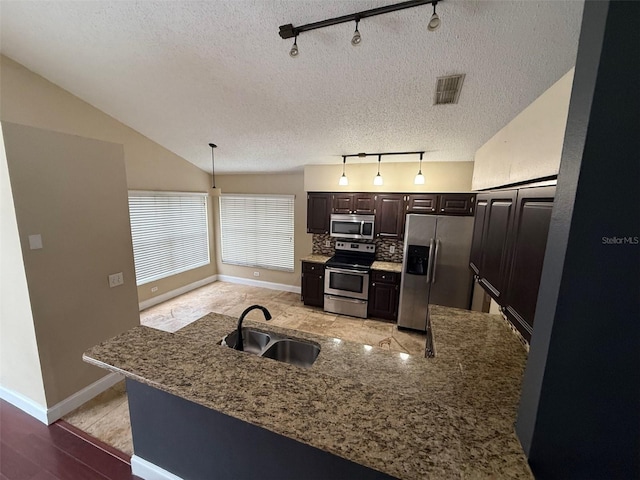 kitchen with stainless steel appliances, sink, tasteful backsplash, dark brown cabinetry, and pendant lighting