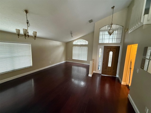 entryway featuring dark hardwood / wood-style floors, high vaulted ceiling, and a chandelier