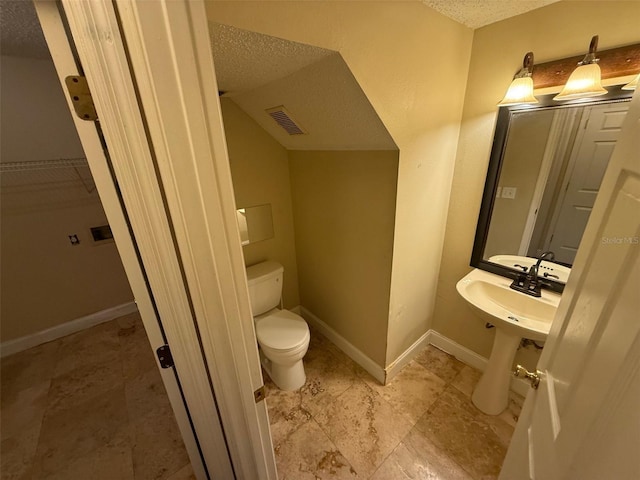 bathroom featuring toilet, a textured ceiling, and vaulted ceiling