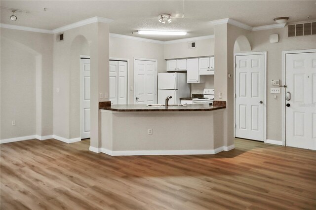 kitchen featuring white appliances, white cabinets, hardwood / wood-style floors, sink, and crown molding