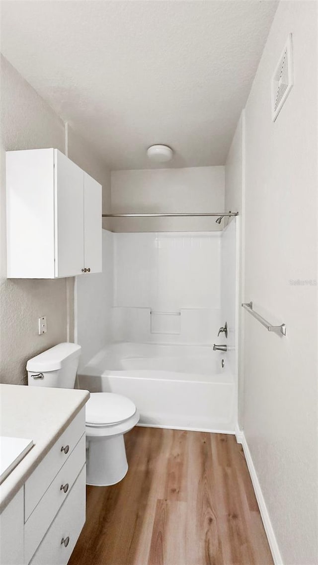 full bathroom with hardwood / wood-style floors, a textured ceiling, vanity, toilet, and shower / bathtub combination