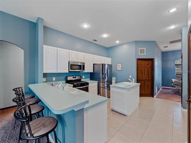 kitchen featuring a kitchen bar, kitchen peninsula, appliances with stainless steel finishes, white cabinets, and sink