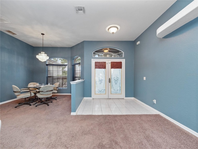 carpeted entrance foyer with french doors and a notable chandelier