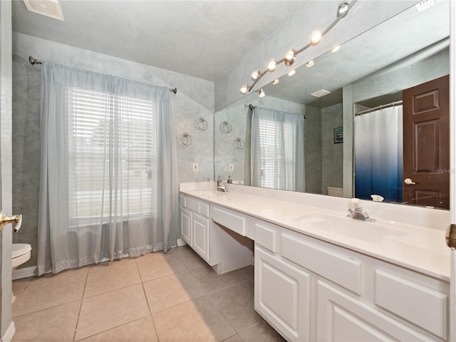 bathroom featuring toilet, vanity, tile patterned floors, and a wealth of natural light