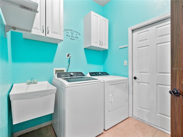 clothes washing area with light tile patterned floors, cabinets, washer and clothes dryer, and sink