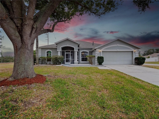 ranch-style house with a garage and a yard