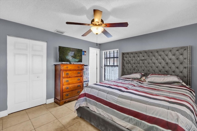 bedroom featuring ceiling fan, a textured ceiling, and light tile patterned floors