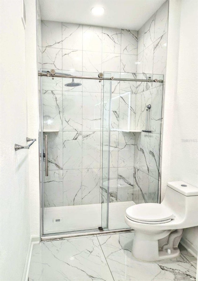 bathroom featuring a shower with shower door and toilet