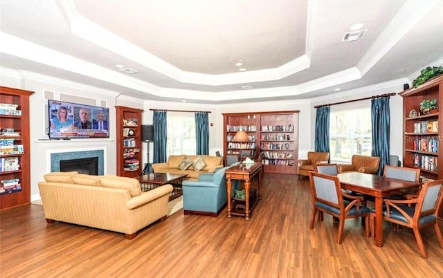 living room featuring a raised ceiling, hardwood / wood-style floors, a wealth of natural light, and crown molding