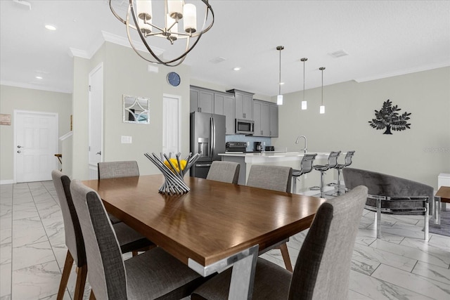 dining area with sink, ornamental molding, and an inviting chandelier