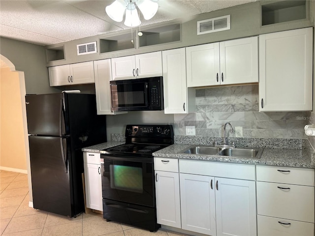 kitchen featuring light tile patterned floors, black appliances, decorative backsplash, white cabinetry, and sink