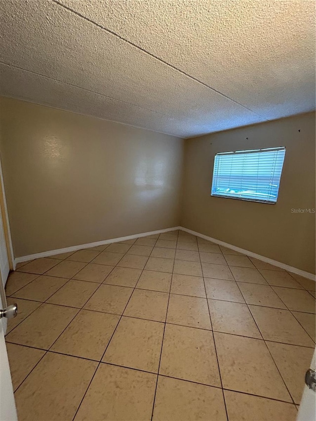 tiled empty room featuring a textured ceiling