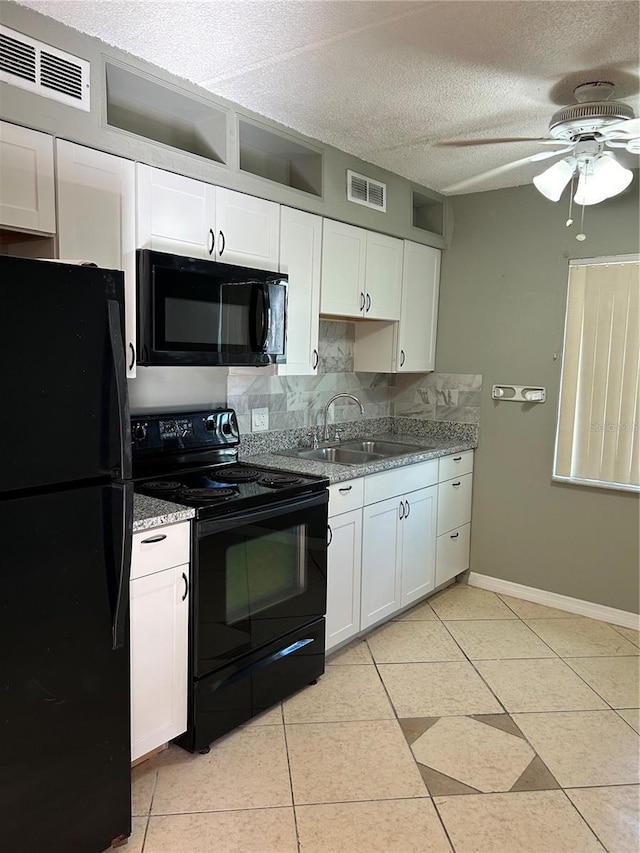 kitchen featuring a textured ceiling, light tile patterned floors, black appliances, white cabinetry, and sink